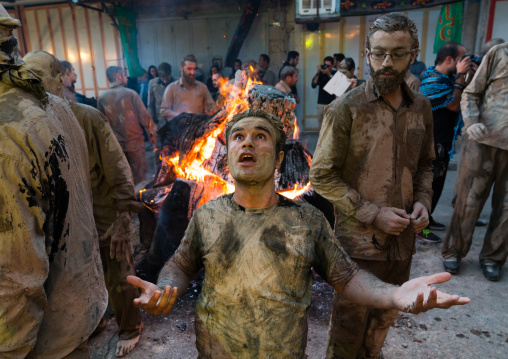 Iranian shiite muslim men gather around a bonfire after rubbing mud on their bodies during the Kharrah Mali ritual to mark the Ashura day, Lorestan Province, Khorramabad, Iran
