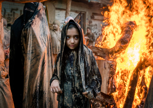 Iranian shiite muslim girls gather around a bonfire after rubbing mud on their chadors during the Kharrah Mali ritual to mark the Ashura day, Lorestan Province, Khorramabad, Iran