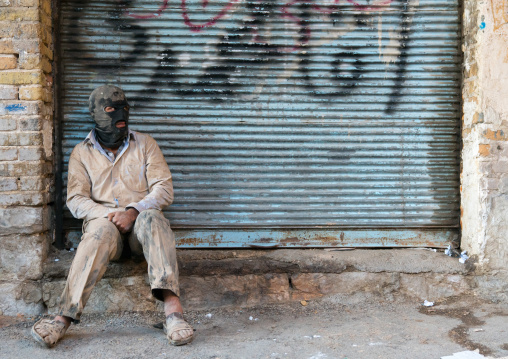 Iranian shiite muslim man resting after rubbing mud on his clothes during the Kharrah Mali ritual to mark the Ashura ceremony, Lorestan Province, Khorramabad, Iran