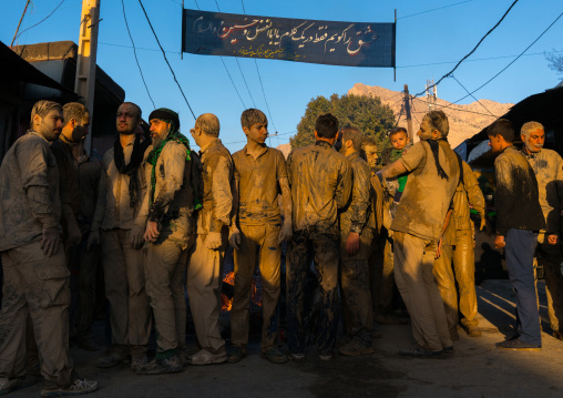 Iranian shiite muslim men gather around a bonfire after rubbing mud on their clothes during the Kharrah Mali ritual to mark the Ashura day, Lorestan Province, Khorramabad, Iran
