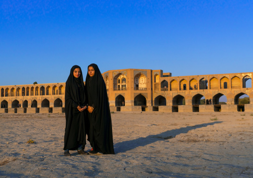 Portrait of two young women in chadors in front of Khaju bridge Pol-e Khaju, Isfahan Province, Isfahan, Iran