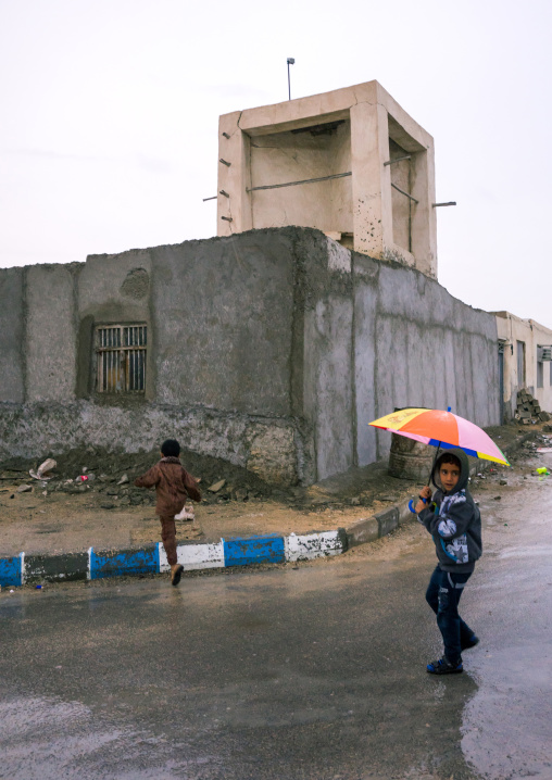 children under the rain in front of a wind tower, Qeshm Island, Salakh, Iran