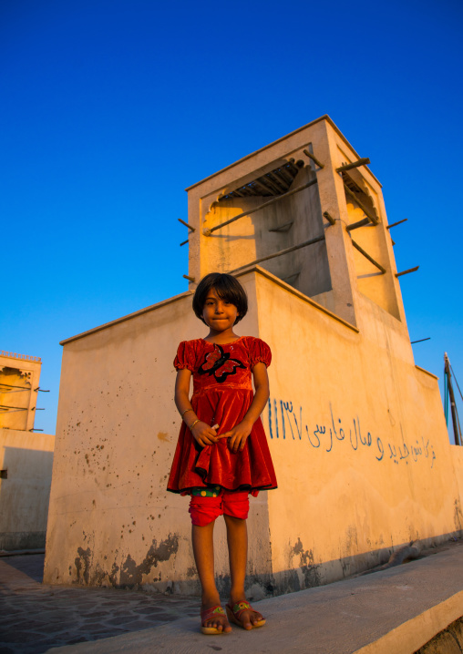 little girl in front of a wind tower used as a natural cooling system, Qeshm Island, Laft, Iran