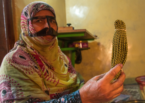 a bandari woman with a traditional mask and showing ropes she uses for the mask, Qeshm Island, Salakh, Iran