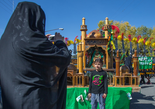 Woman Taking Picture In Front Of A Trolley Where Are Sold Green Ribbons During Ashura Celebration, Kurdistan Province, Bijar, Iran