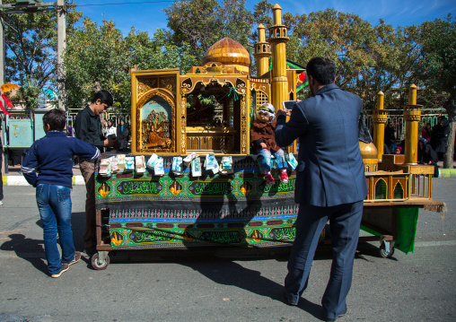 Man Taking Picture In Front Of A Trolley Where Are Sold Green Ribbons During Ashura Celebration, Kurdistan Province, Bijar, Iran