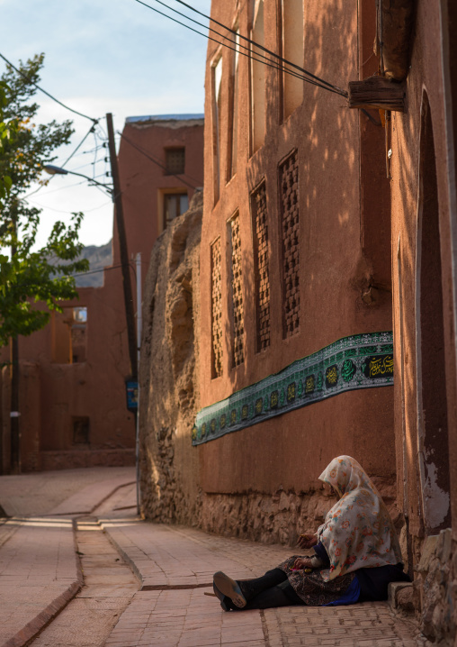 Sitting Woman Sitting In Front Of An Ancient Building With Ashura Decoration In Zoroastrian Village, Isfahan Province, Abyaneh, Iran
