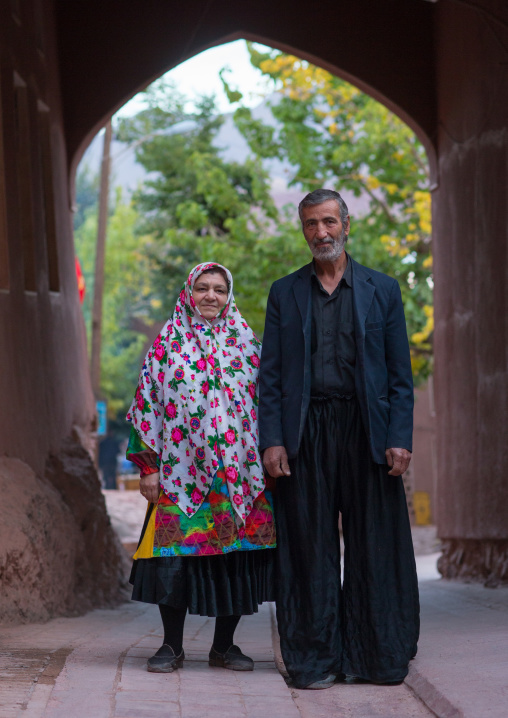 Portrait Of An Iranian Woman Wearing Traditional Floreal Chador With Her Husband In Zoroastrian Village, Isfahan Province, Abyaneh, Iran