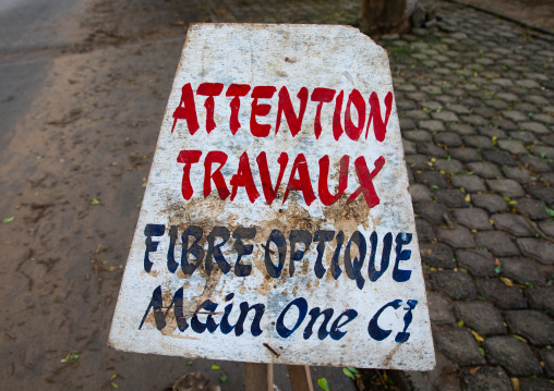 Warning billboard in the street about a  construction site for internet optic fiber, Sud-Comoé, Grand-Bassam, Ivory Coast
