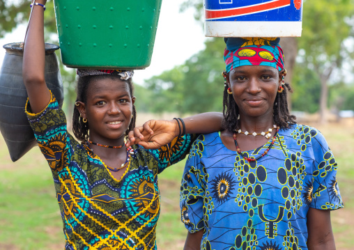 Portrait of Peul tribe girls carrying buckets full of water on the head, Savanes district, Boundiali, Ivory Coast