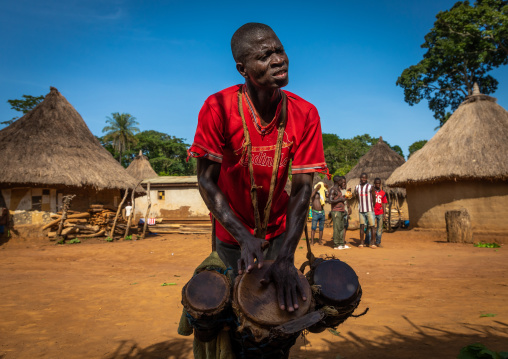 Dan tribe man beating the drums during a ceremony, Bafing, Gboni, Ivory Coast