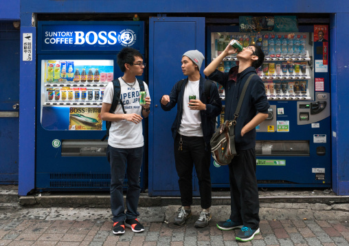 Young men using a drinks vending machine, Kanto region, Tokyo, Japan