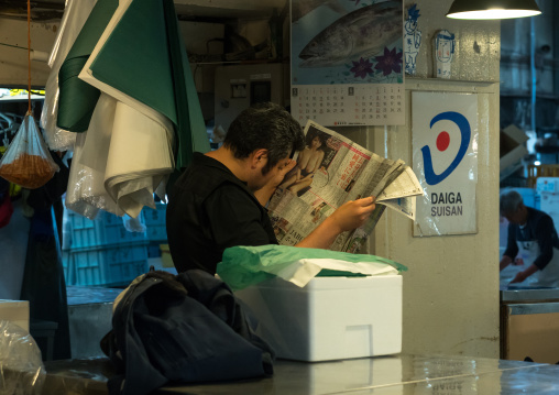 Vendor reading a newspaper in tsukiji fish market, Kanto region, Tokyo, Japan