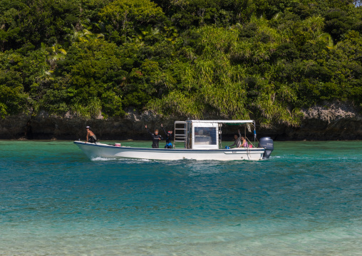 Divers boat in tropical lagoon with clear blue water surrounded by lush greenery in Kabira bay, Yaeyama Islands, Ishigaki, Japan