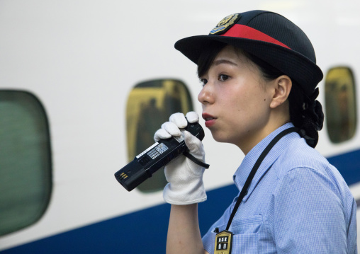 Japanese female station master speaking in a microphone in front of a Shinkansen train in a station, Hypgo Prefecture, Himeji, Japan