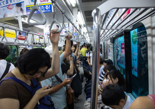 Japanese passengers in the subway using their mobile phones, Kanto region, Tokyo, Japan