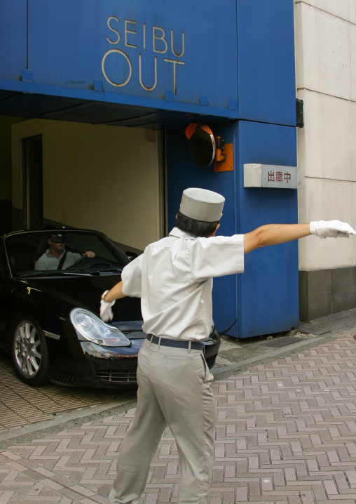 japanese security guard helping a car going out of a parking, Kanto region, Tokyo, Japan
