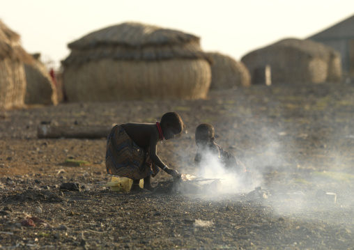 Grass huts and children making fire in el molo tribe village, Turkana lake, Loiyangalani, Kenya