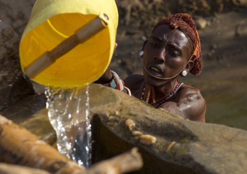 Rendille tribe man taking water in a singing well for his camels, Marsabit district, Ngurunit, Kenya