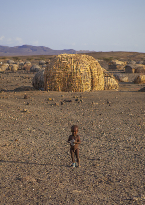 Naked baby in front of grass huts in el molo tribe village, Turkana lake, Loiyangalani, Kenya