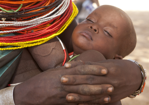 Rendille tribeswoman holding her sleeping baby, Marsabit district, Ngurunit, Kenya