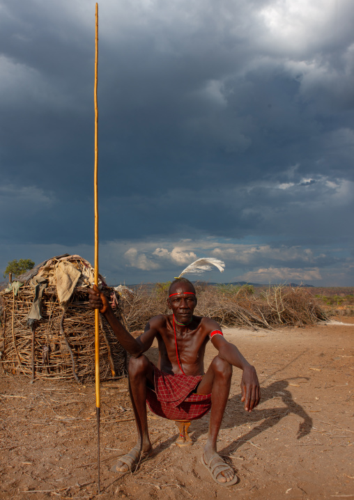 Portrait of a Pokot tribe man sit on his wooden pillow holding a spear, Baringo County, Baringo, Kenya