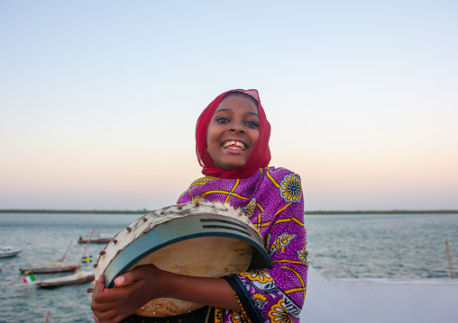 Portrait of a smiling swahili girl playing drum, Lamu County, Lamu, Kenya