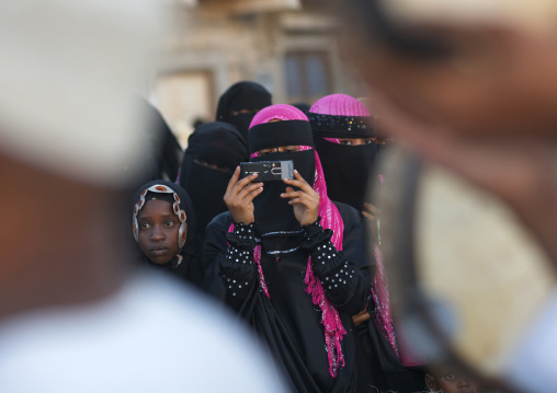 A muslim woman in burqa taking a photo during Maulid festival, Lamu County, Lamu, Kenya