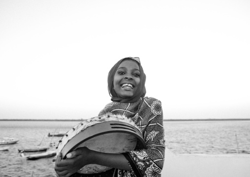 Portrait of a smiling swahili girl playing drum, Lamu County, Lamu, Kenya