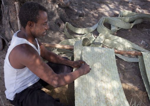 Kenyan man weaving a rug sitting on the floor, Lamu County, Matondoni, Kenya