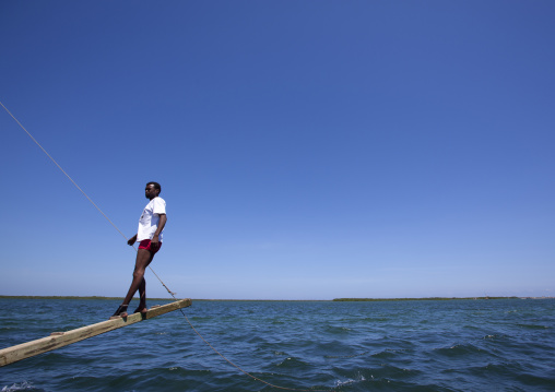 Man balancing dhow while sailing during the Maulid festival race, Lamu County, Lamu, Kenya