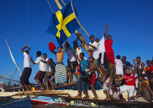 Swedish flagged dhow with crew cheering themselves during the Maulid festival race, Lamu County, Lamu, Kenya