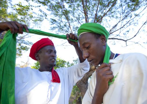 Muslim man putting a turban on another man head during Maulid festival, Lamu County, Lamu, Kenya