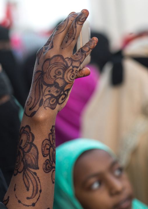 Sunni muslim woman with henna taking pictures during the maulidi festivities in the street, Lamu county, Lamu town, Kenya
