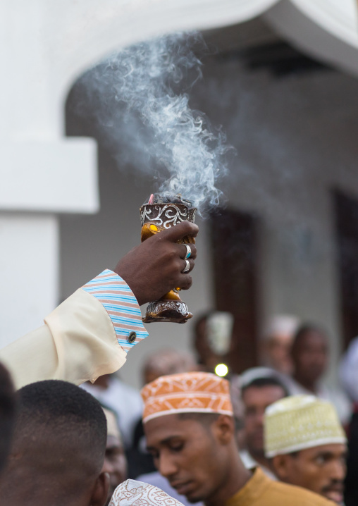 Sunni muslim man spreading insence with a censer during the maulidi festivities in the street, Lamu county, Lamu town, Kenya