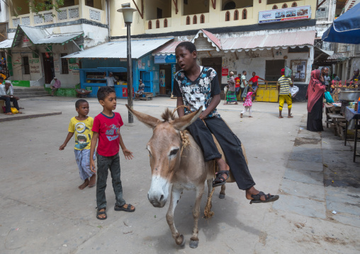 Child riding a donkey on a square, Lamu county, Lamu town, Kenya