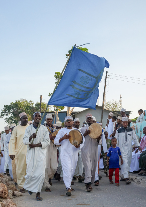 Sunni muslim people parading with flags during the maulidi festivities in the street, Lamu county, Lamu town, Kenya