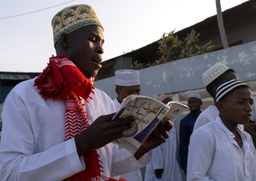 Sunni muslim man reading a religious book during the maulidi festivities in the street, Lamu county, Lamu town, Kenya
