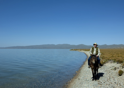 Western Man Riding A Horse On The Shores Of Song Kol Lake, Jaman Echki Jailoo Village, Kyrgyzstan
