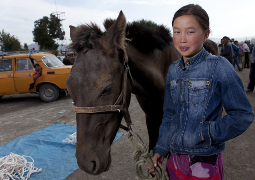 Young Woman Holding A Horse By The Bridle At The Animal Market Of Kochkor, Kyrgyzstan