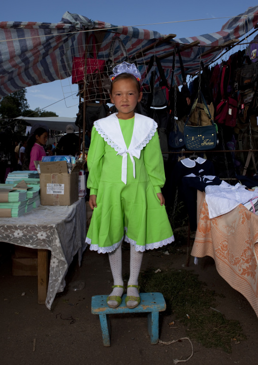 Young Girl In Green Traditional Dress Standing On A Stool, Kochkor Animal Market, Kyrgyzstan