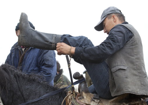 Man Getting Off His Horse, Saralasaz Jailoo In Song Kol Lake Area, Kyrgyzstan
