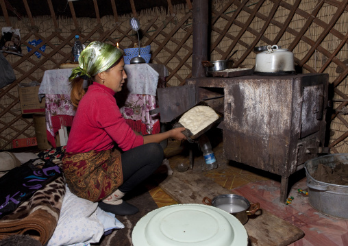 Woman With Headscarf Baking Food In An Oven Inside Her Hut, Jaman Echki Jailoo Village, Kyrgyzstan
