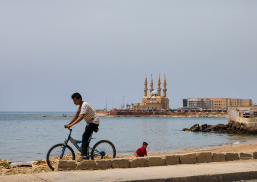 Child on a bicycle in front of corniche el Mina mosque, North Governorate, Tripoli, Lebanon