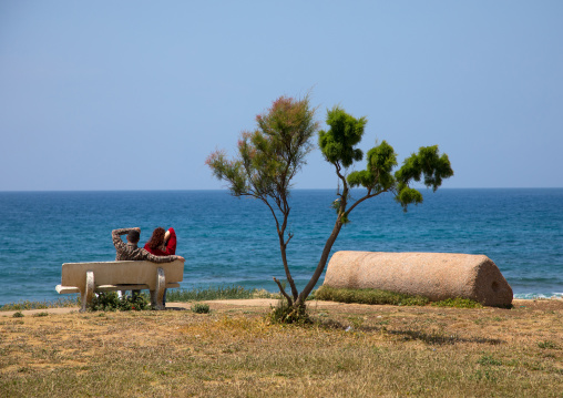 Couple sits on a bench in front of the sea, South Governorate, Tyre, Lebanon
