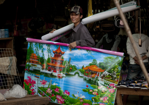 Man selling a chinese poster on a market, Phonsaad, Laos