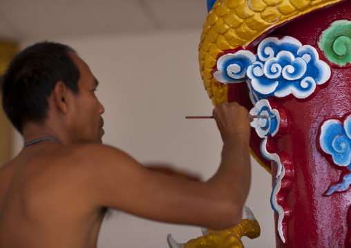 Man painting a pillar in a temple, Pakse, Laos