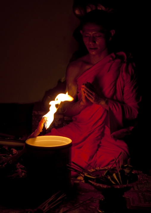 Monk praying in front of a fire, Luang prabang, Laos
