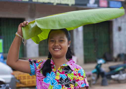 Hmong minority woman protecting herself from the rain with a banana leaf, Luang prabang, Laos