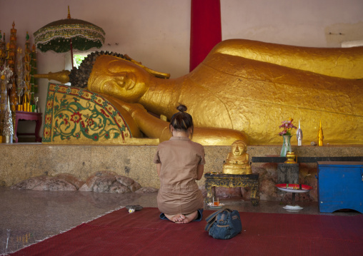 Man praying in front of lying buddha in pha bat monastery, Pakse, Laos
